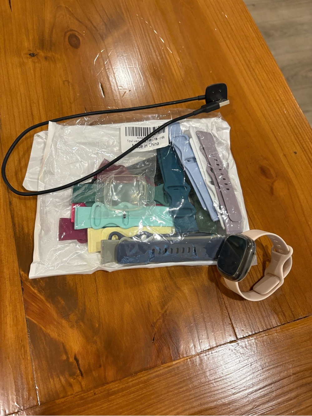 Fitbit versa 3 smartwatch with multiple colorful silicone bands and charger